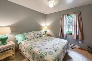 Ein Schlafzimmer mit einem Bett, zwei Nachttischlampen, einem Fenster mit Vorhängen und einer Heizung.