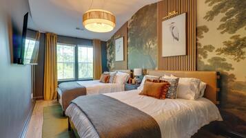 A hotel room with two beds, a large window, a painting on the wall, and a ceiling light.