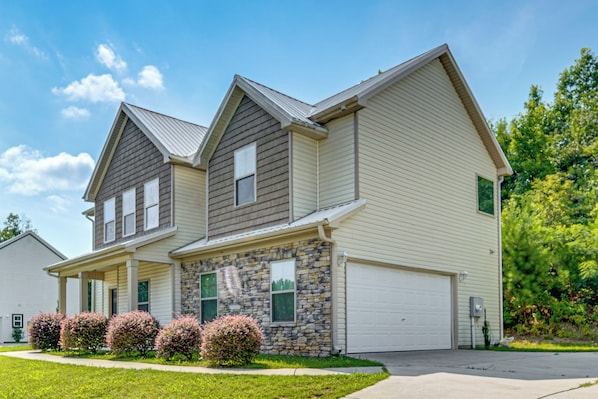 A two-story residential building with a stone facade, a garage, and a well-maintained lawn.
