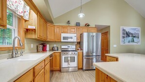 A modern kitchen with wooden cabinets, stainless steel appliances, and a view of a mountain lake through an open window. - Unplug & Unwind! Romulus Family Gem w/ Swim Pond (Romulus)