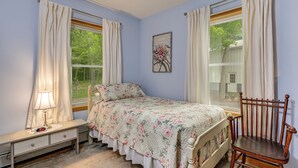A bedroom with a bed, a chair, a nightstand, and a window with curtains. - Unplug & Unwind! Romulus Family Gem w/ Swim Pond (Romulus)