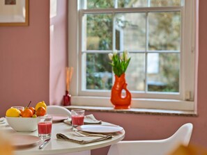 A breakfast table with fruits, a glass of juice, and a vase with flowers. - Historic Wiltshire Garden Cottage (Trowbridge)