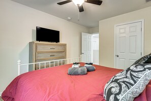 A bedroom with a bed, a dresser, a television, and a door.