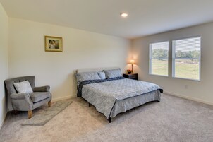 Quarto com cama, poltrona, mesa de cabeceira, luminária e janela.