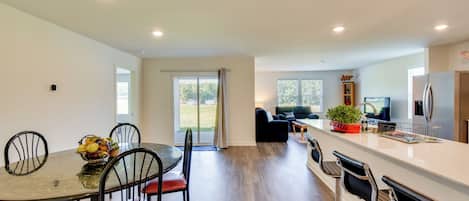 A modern kitchen with a dining area, a large window, and a view of the outdoors.