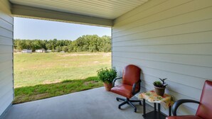 Eine überdachte Veranda mit zwei Stühlen, einem kleinen Tisch und Blumentöpfen.