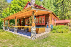 A log cabin with a porch, stone pillars, and a hot tub. - 700-acre Property w/ 33-acre Lake & Dual Cabins! (Chewelah)