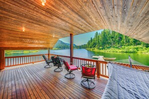A wooden deck with outdoor seating, a view of a lake, and a forested landscape.