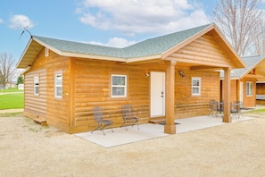 A log cabin with a covered porch, two chairs, and a table.