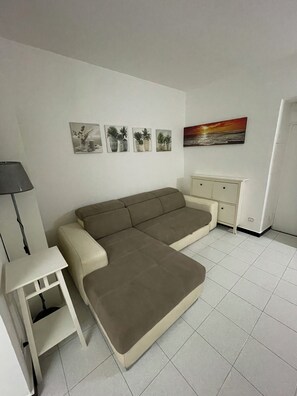 A room with a sofa, a small table, a cabinet, and wall art. - Center in the city of Genoa (Genova)