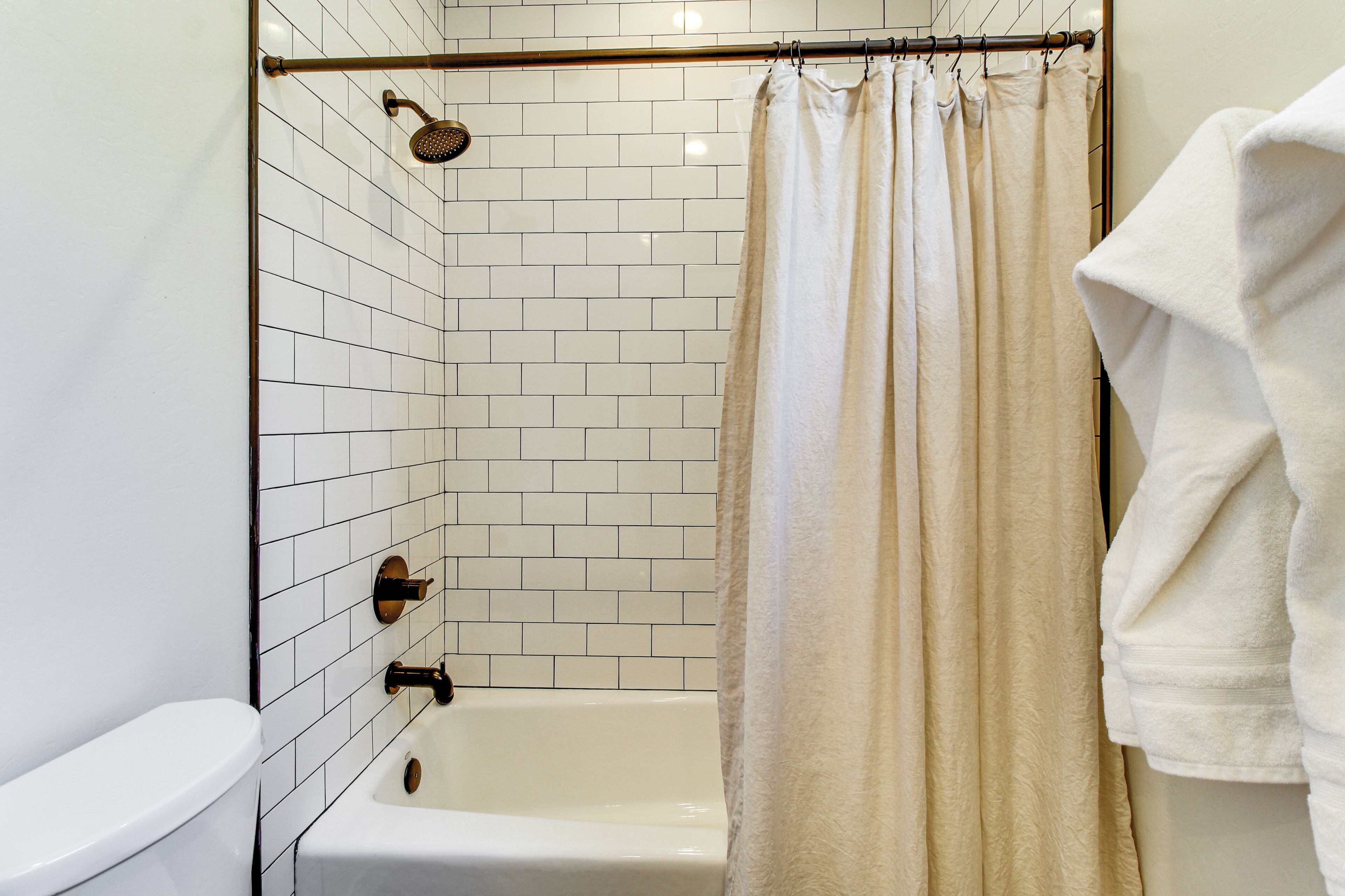 A bathroom with a white tiled shower enclosure, a bathtub, and a toilet.