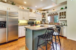 A kitchen with a central island, bar stools, a stainless steel refrigerator, and wooden cabinetry. - Deck, Fire Pit, Hot Tub! Pinetop Family Cabin (Pinetop)
