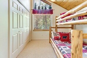 A bunk bed with a forest view, a window with blinds, and a door with a white frame. - Deck, Fire Pit, Hot Tub! Pinetop Family Cabin (Pinetop)