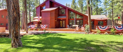 Une cabane en bois à deux étages, dotée d’une grande terrasse et d’un mât pour hisser un drapeau.