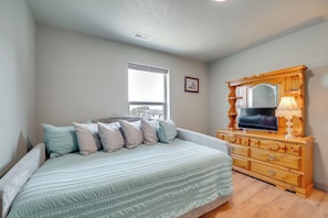 Un dormitorio con cama, cómoda y ventana.