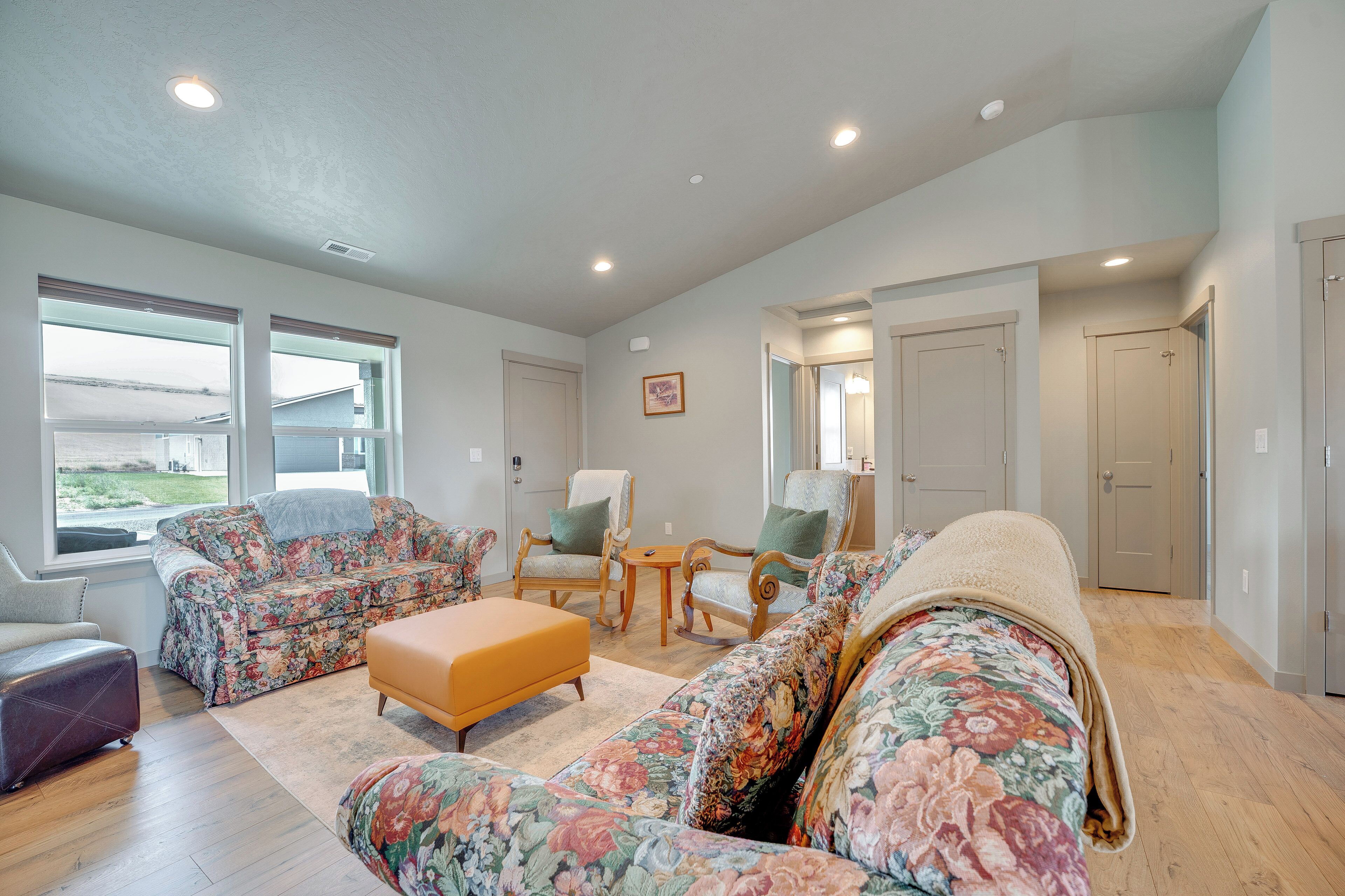 A spacious living room with floral-patterned sofas, a wooden coffee table, and a rocking chair.