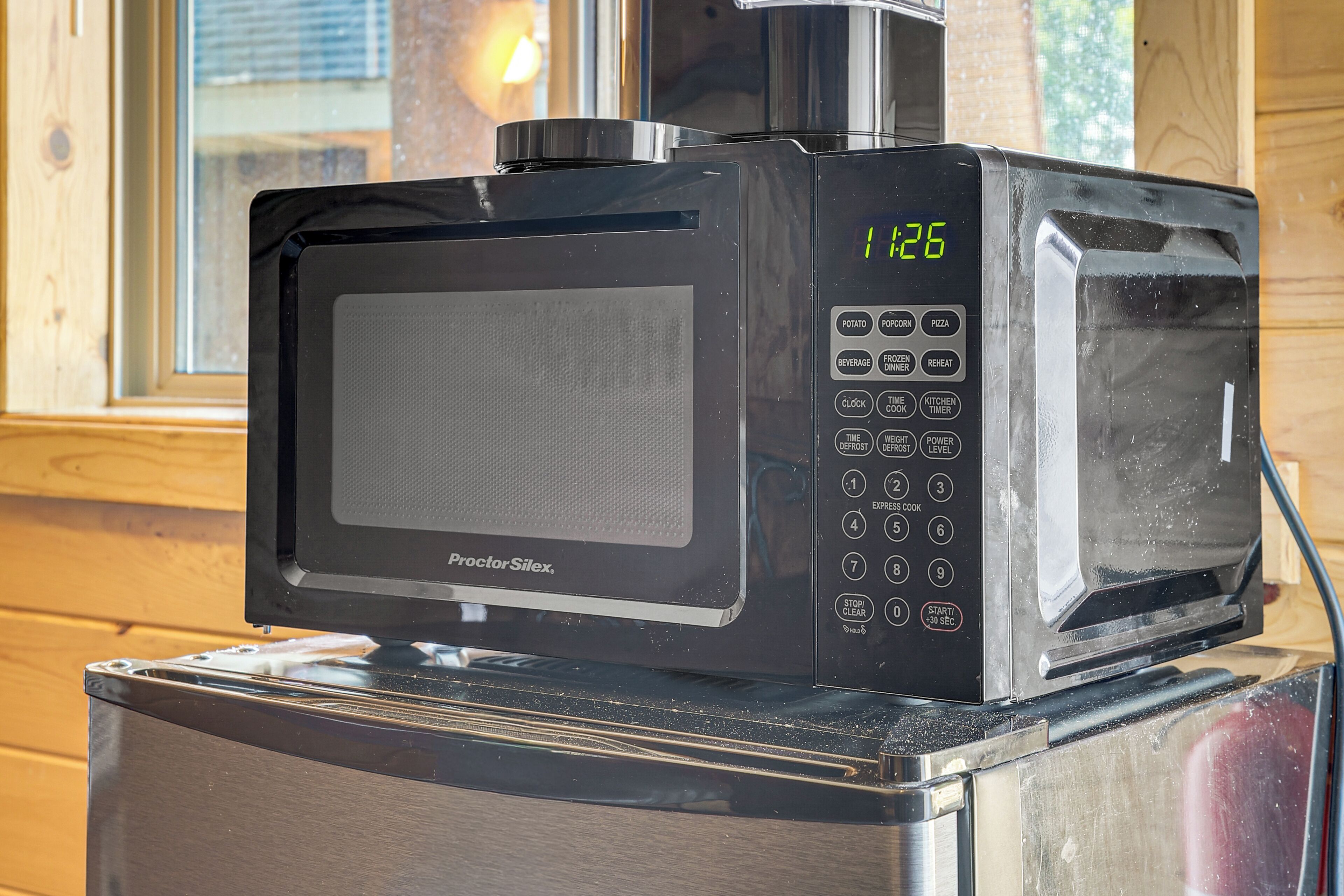 A black microwave oven with a digital display on a wooden surface.