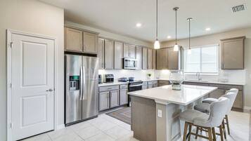 A modern kitchen with stainless steel appliances, a central island, and pendant lighting.
