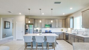 A modern kitchen with a central island, bar stools, stainless steel appliances, and pendant lighting. - Home Office! Mascotte Family Escape Near Hospital (Mascotte)