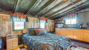 A bedroom with a bed, a wooden wardrobe, a small desk, and a kitchenette. - Cast & Relax! Lake-view Fishing Cabin in Monmouth (Monmouth)