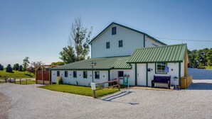 A large white building with a green roof, a gravel driveway, and a wooden fence. - Cast & Relax! Lake-view Fishing Cabin in Monmouth (Monmouth)
