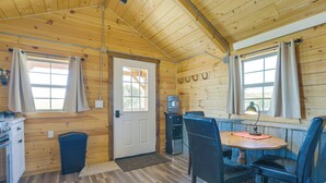 A wooden cabin interior with a dining area, a water dispenser, and a door leading outside.