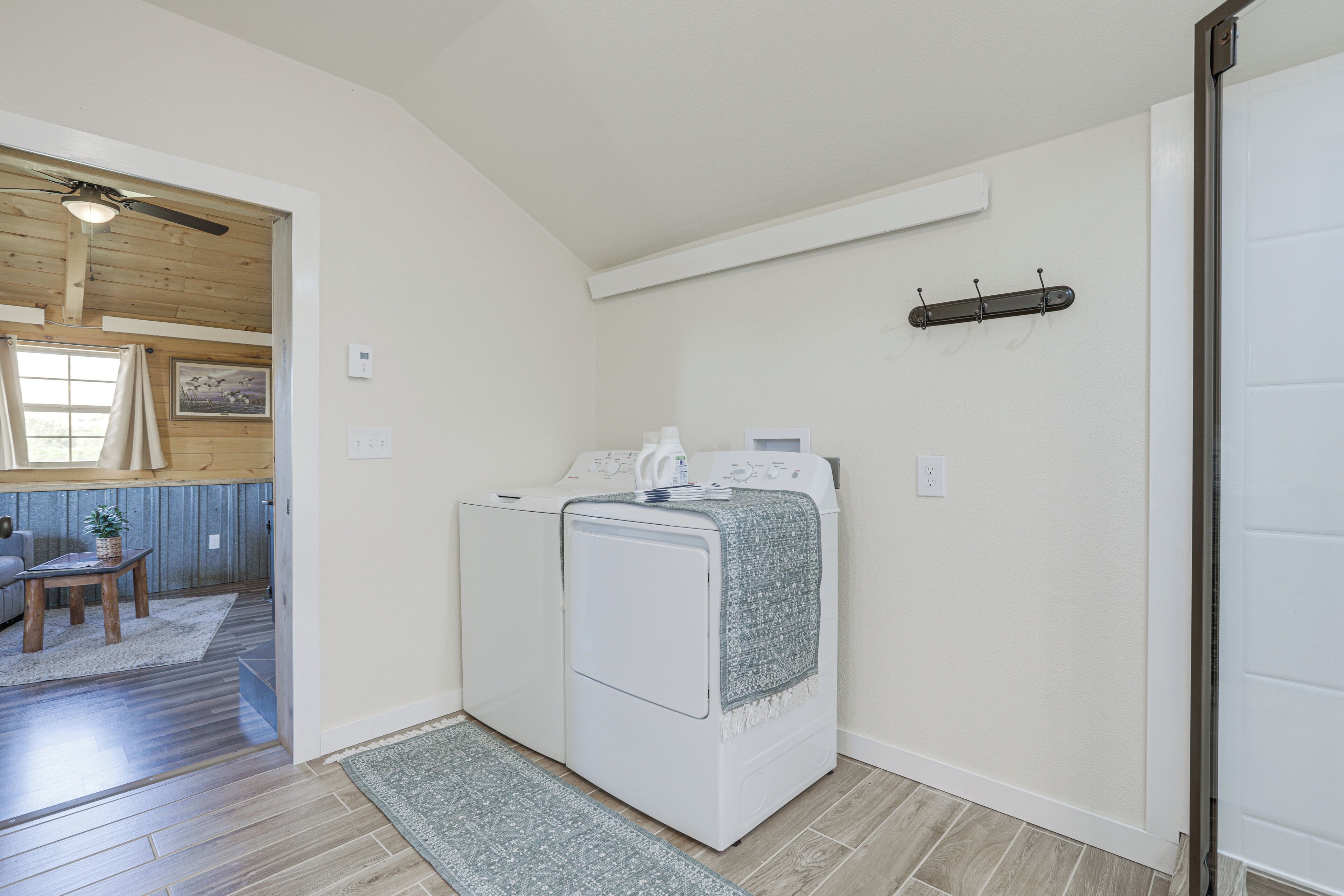 A laundry room with a washing machine and dryer, a small table with a plant, and a door leading to another room.