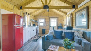 Un acogedor interior de cabaña con cocina, comedor y sala de estar, que incluye un sofá y una mesa.