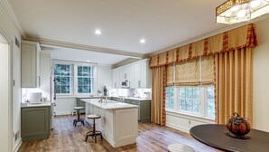 Una cocina moderna con una isla central, taburetes de bar y una mesa de comedor.
