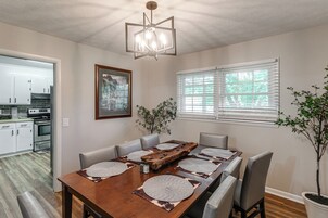 Un comedor con una mesa de madera, seis sillas y una araña.