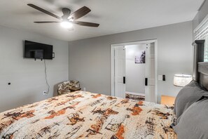 A bedroom with a bed, a ceiling fan, a mounted TV, and a door leading to another room. - Great for Groups! Pet-friendly Getaway in Vidalia (Vidalia)
