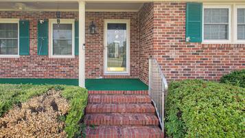 A brick building with a front porch, a door, and a small set of steps leading to the entrance.