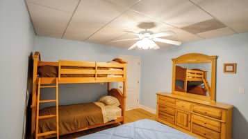 A bedroom with bunk beds, a dresser, and a ceiling fan.