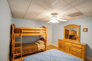 Une chambre avec des lits superposés, une commode et un ventilateur de plafond.