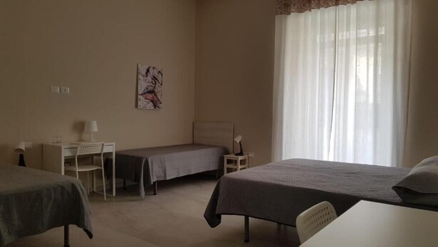 Een hotelkamer met twee bedden, een bureau, een stoel en een raam met gordijnen.