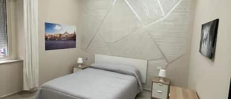 A modern bedroom with a bed, bedside tables, and a wall-mounted artwork.