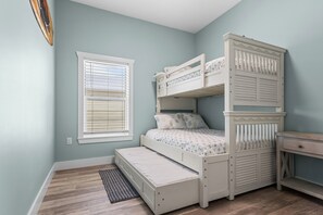 Ein Kinderstockbett mit Schreibtisch und Fenster mit Jalousien.