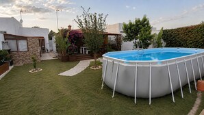 Ein Garten mit Schwimmbad, einem Kiesweg und verschiedenen Pflanzen.