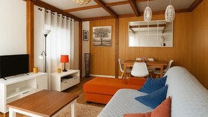 Ein modernes Wohnzimmer mit Fernseher, Sofa und Essbereich.