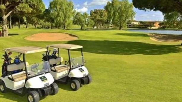 Ein Golfplatz mit zwei Golfwagen, die auf dem Grün geparkt sind.