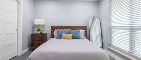 A bedroom with a bed, bedside table, lamp, and a ceiling fan.