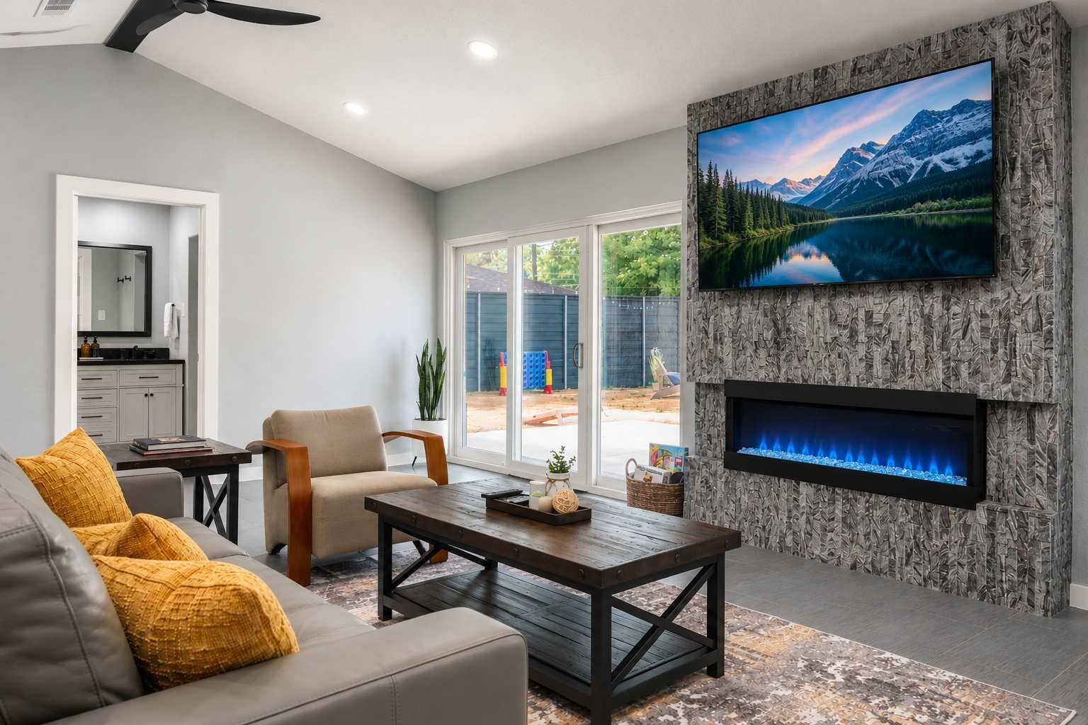 Una sala de estar moderna con chimenea, televisor montado en una pared con textura y vistas a un paisaje montañoso.