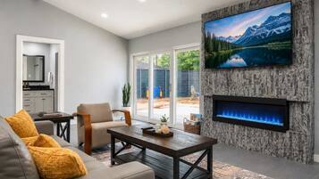 Una sala de estar moderna con chimenea, televisor montado en una pared con textura y vistas a un paisaje montañoso.