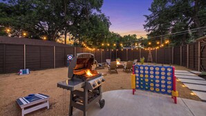 An outdoor backyard with a barbecue grill, seating area, and a children's play structure. - Bright Dallas Retreat with Fire Pit & Games (Dallas)
