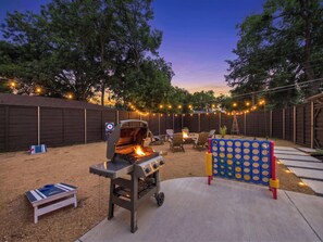 An outdoor backyard with a barbecue grill, seating area, and a children's play structure. - Bright Dallas Retreat with Fire Pit & Games (Dallas)