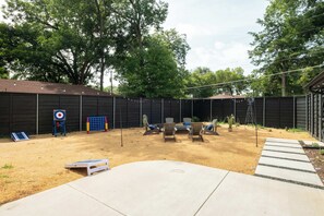 A backyard with a target practice area, outdoor seating, and a wooden fence. - Bright Dallas Retreat with Fire Pit & Games (Dallas)