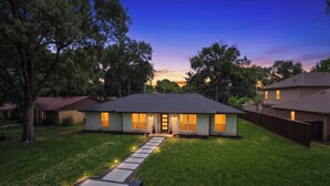 A two-story house with a well-maintained lawn and a pathway leading to the front door. - Bright Dallas Retreat with Fire Pit & Games (Dallas)