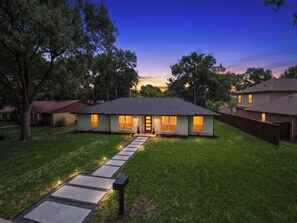 A two-story house with a well-maintained lawn and a pathway leading to the front door. - Bright Dallas Retreat with Fire Pit & Games (Dallas)
