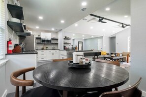A modern kitchen with white cabinets, a stainless steel refrigerator, and a dining area with a round table and chairs. - Bright Dallas Retreat with Fire Pit & Games (Dallas)