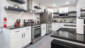 A modern kitchen with white cabinetry, stainless steel appliances, and black countertops. - Bright Dallas Retreat with Fire Pit & Games (Dallas)